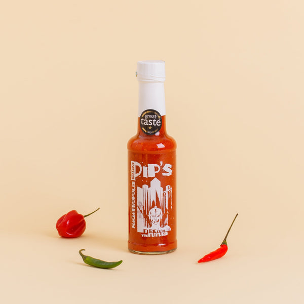 Pip's Nagatropolis Extra Hot Sauce bottle with a white cap and a "Great Taste" award sticker, surrounded by red and green chilli peppers on a neutral background.
