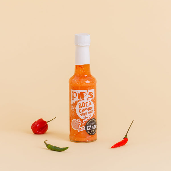 A bottle of Pip’s Boca Grande Very Hot Sauce standing upright against a beige background. The label displays the text "Pip's Boca Grande Very Hot Sauce" along with a "Great Taste" award sticker, flanked by a red pepper on the left and a green and red chili pepper on the right.